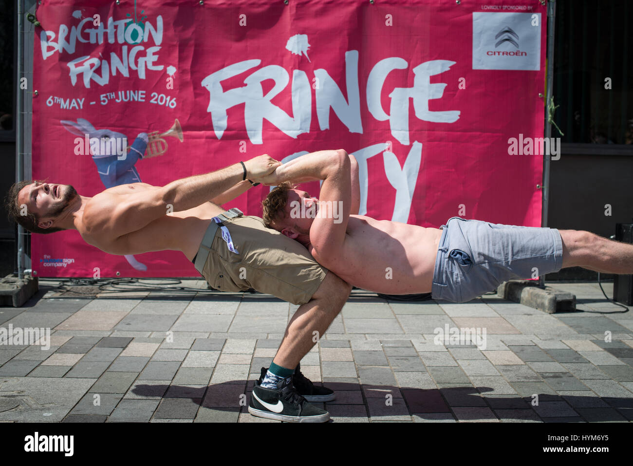 Ein männlicher Acrobat hält seinen Freund in der Luft während eines Straße Leistung im Brighton Fringe in Brighton, East Sussex, UK, England. Stockfoto