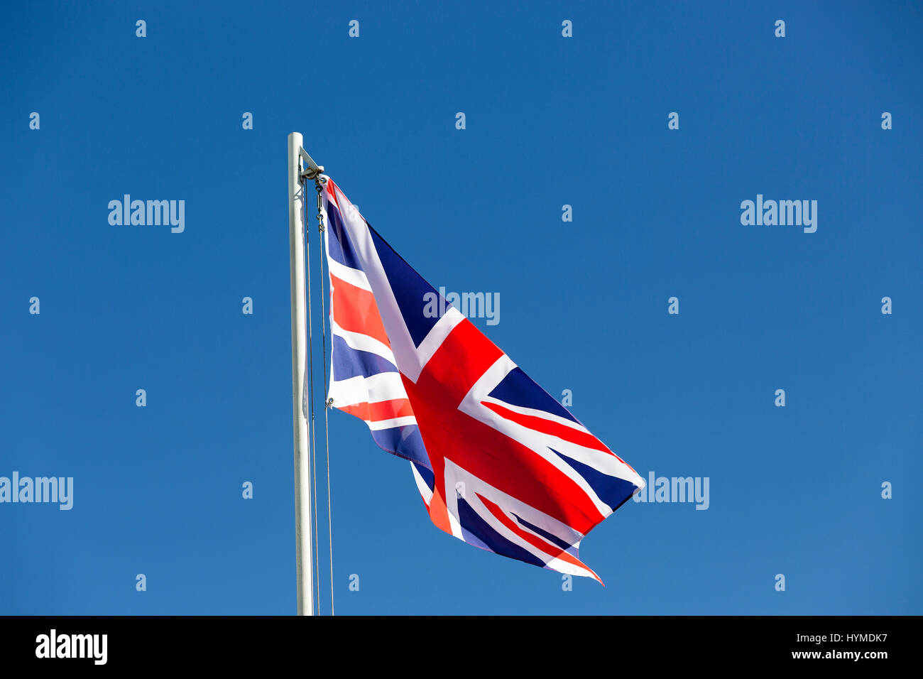 Britische Flagge am Fahnenmast vor blauem Himmel Stockfoto