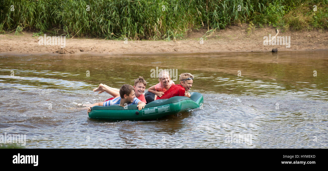 Vier Kinder schwimmen auf dem Fluss Pilica auf einem Schlauchboot. Polnische Mädchen 8 Jahre, jungen im Alter von 10, 11, 12. Rzeczyca Zentralpolen Europa Stockfoto