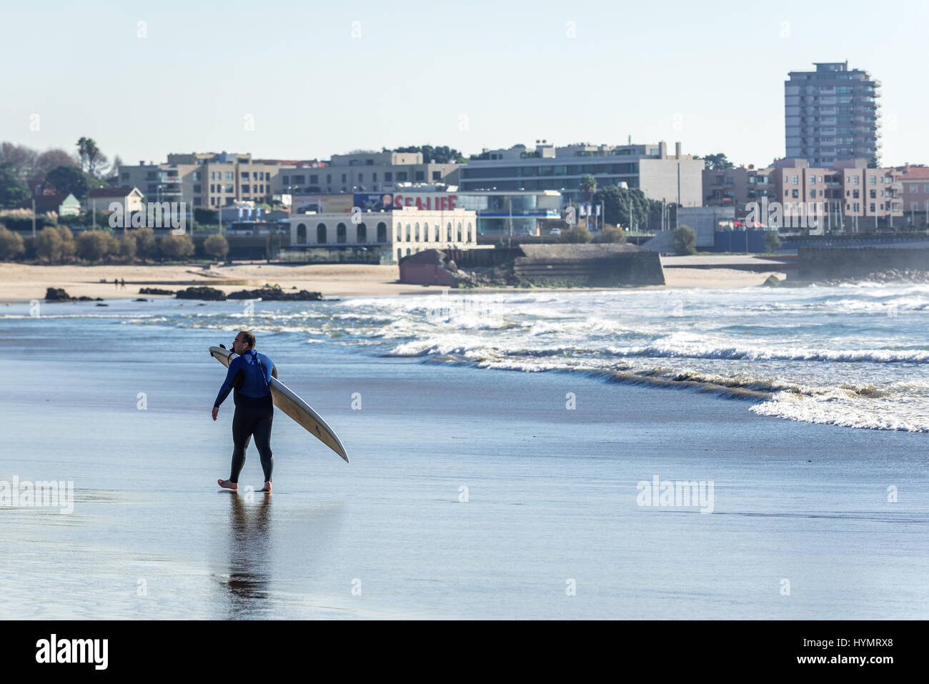 Mann mit Surf Board am Strand in Matosinhos Stadt, eingefaßt mit Porto, Teil der Subregion Grande Porto in Portugal Stockfoto
