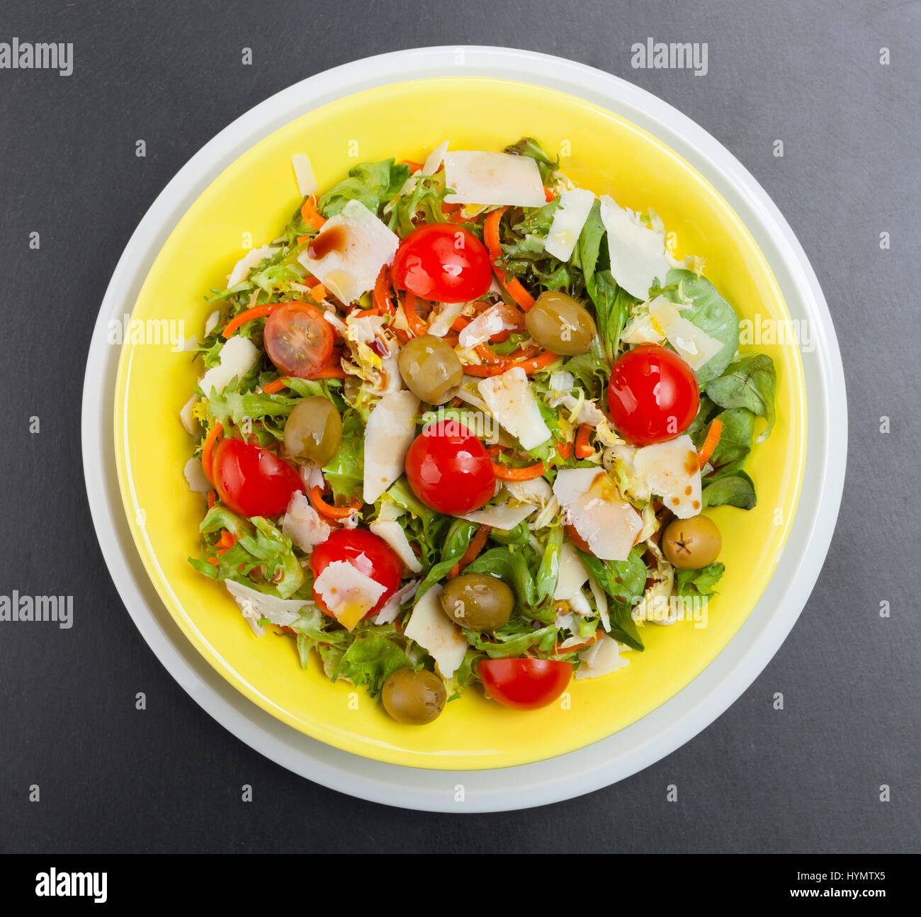 Gemischter Salat von oben mit Oliven, Käse und Tomaten auf schwarzem Schiefer. Stockfoto