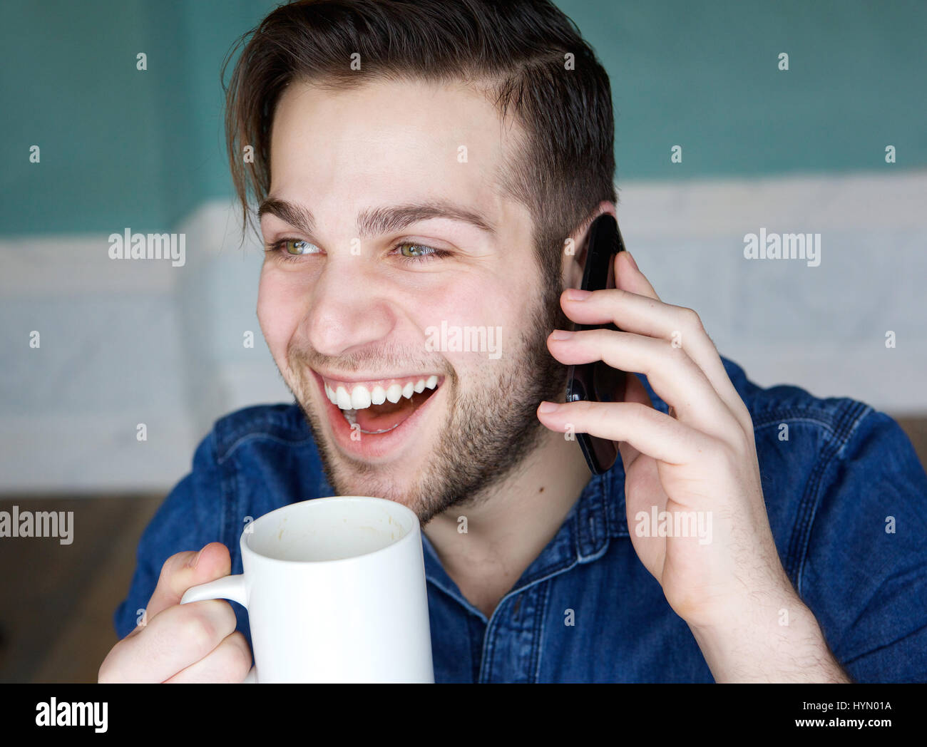 Porträt eines jungen Mannes, die Tasse Kaffee während am Telefon hautnah Stockfoto