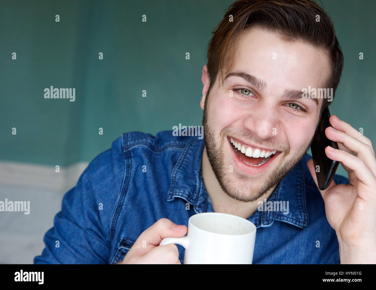 Porträt eines jungen Mannes telefonieren mit Handy mit Tasse Kaffee hautnah Stockfoto