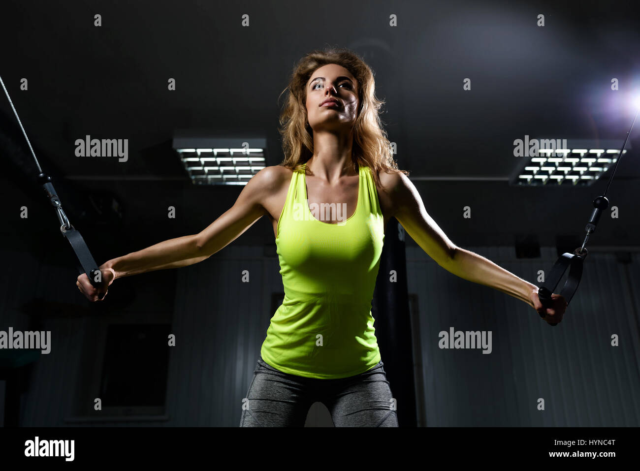 Schöne Blondine mit Riemenscheiben, um ihre Muskeln im Fitnessstudio Stockfoto