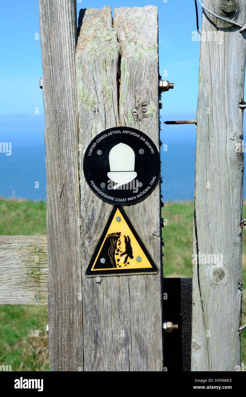 Gefährlichen Klippen Gefahr des fallenden Zeichen und Eichel-Logo auf einem hölzernen Zaun Cemaes Kopf Natur Reserve St. Dogmaels Pembrokeshire Wales Cymru UK GB Stockfoto