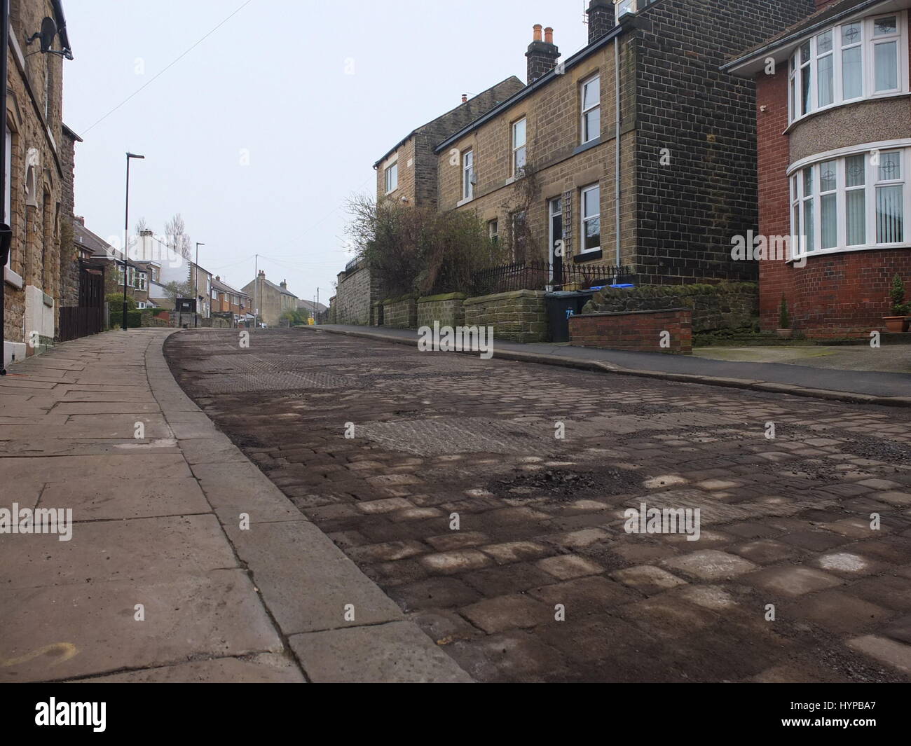 Altes Kopfsteinpflaster auf der Fahrbahn zeigen sich vor der Straße Oberflächenersatz Arbeit auf Walkley Crescent Road, Sheffield Stockfoto