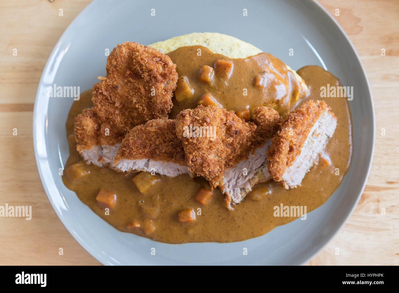 Omelett mit Japanischen Reis Curry und panierte Frittierte Schweinekotelett auf modernen Holz Tisch Stockfoto