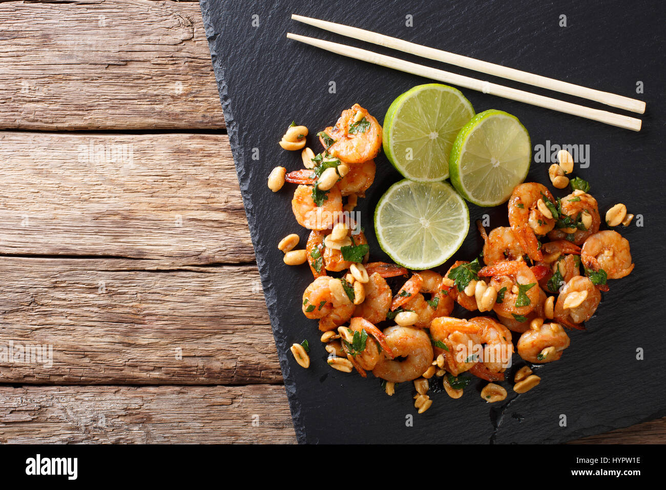 Asiatische Küche: sautierten Garnelen mit Erdnüssen, Kalk und grünen Closeup auf dem Tisch. Horizontale Ansicht von oben Stockfoto