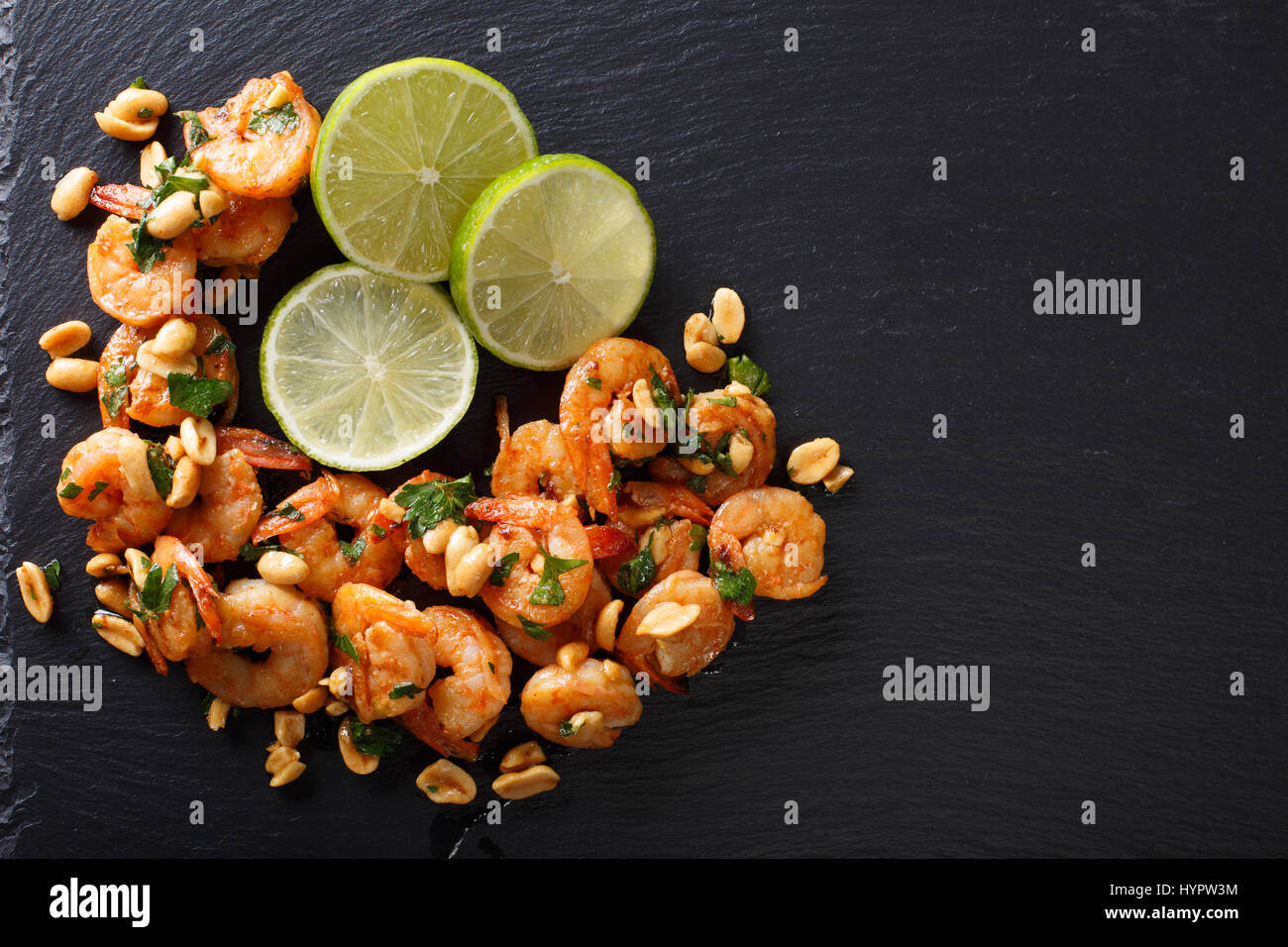 Spicy sautierten von Garnelen, Erdnüsse, Kalk und Kräuter Closeup auf dem Tisch. Horizontale Ansicht von oben Stockfoto