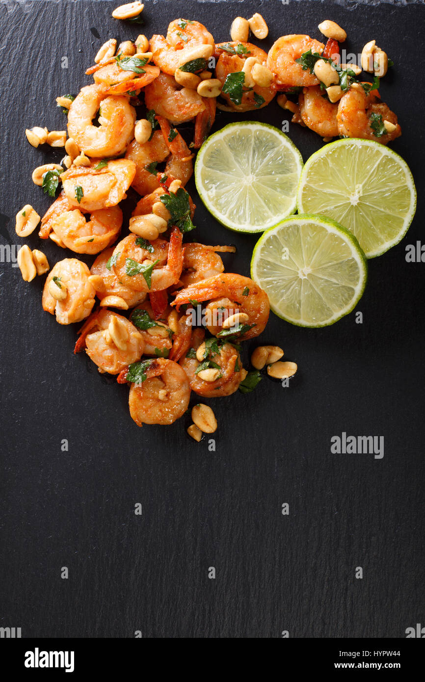 Spicy sautierten von Garnelen, Erdnüsse, Kalk und Kräuter Closeup auf dem Tisch. Vertikale Ansicht von oben Stockfoto