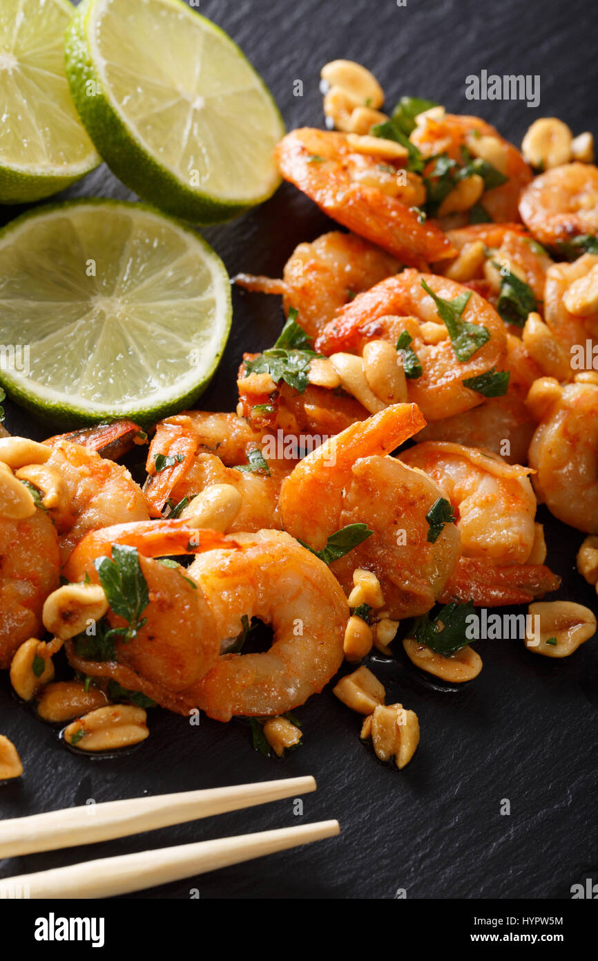 Spicy sautierten von Garnelen, Erdnüsse, Kalk und Kräuter Closeup auf dem Tisch. vertikale Stockfoto