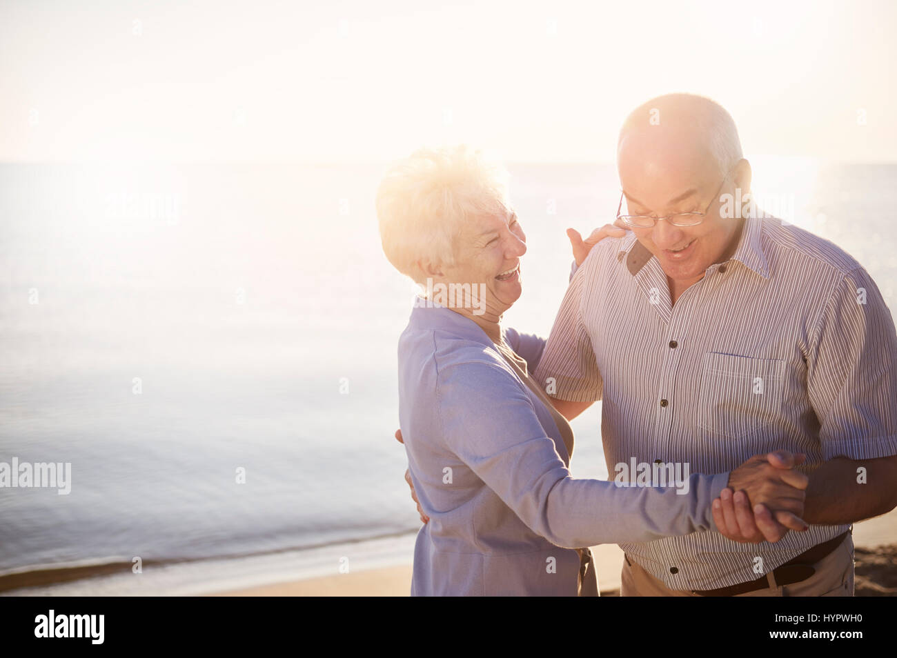 Senioren auf den Sonnenaufgang am Strand tanzen Stockfoto