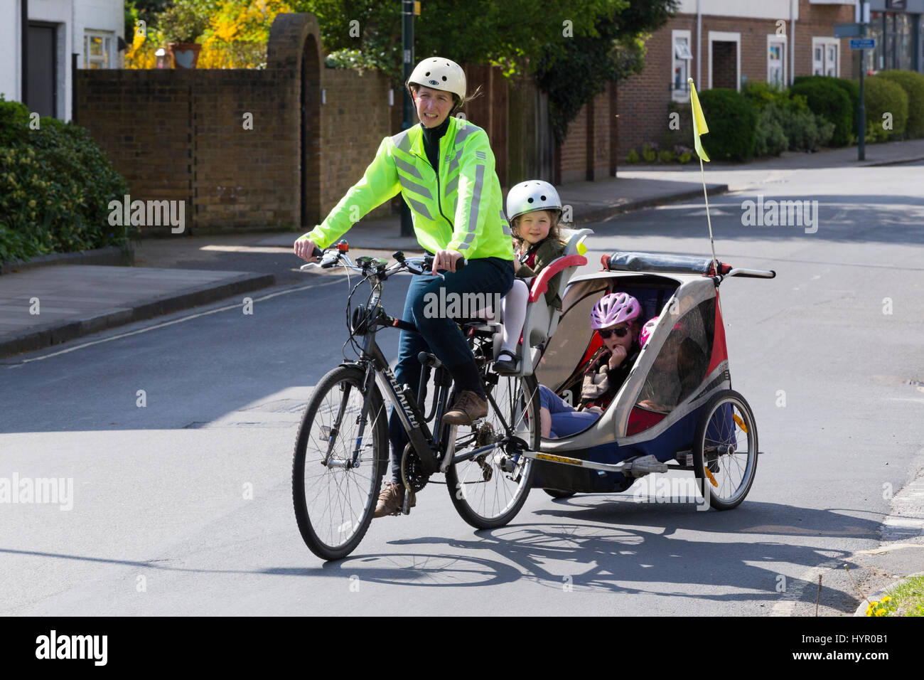 Frau Radfahrer auf Bike / Fahrrad mit + 3 Kinder; Co-Pilot Kindersitz mit  Helm & Abschleppen Zyklus Chariot Anhänger mit zwei / 2 Kinder mit Helmen.  VEREINIGTES KÖNIGREICH Stockfotografie - Alamy