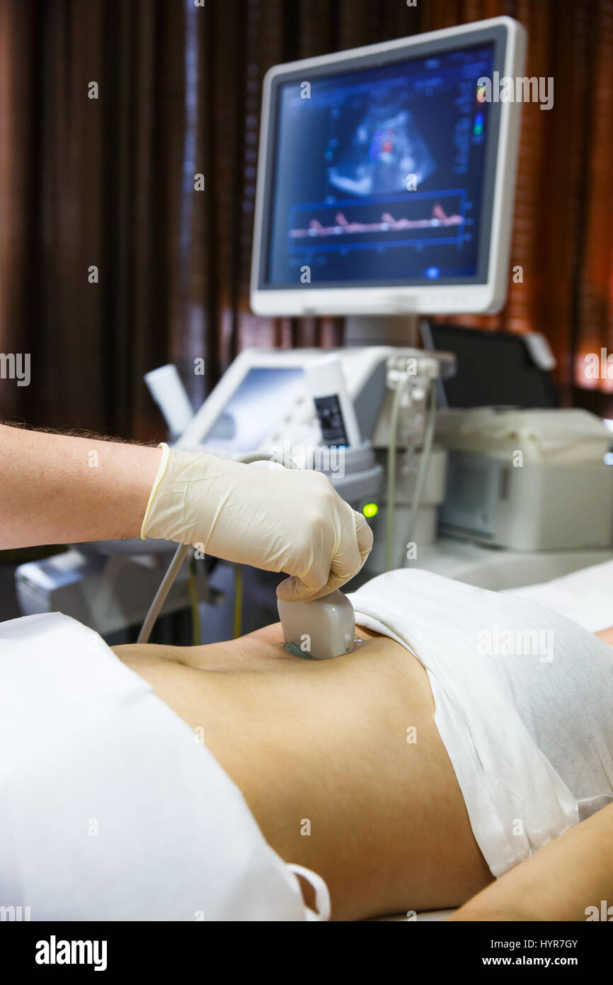 Arzt in einem Krankenzimmer Diagnose eine Ultraschalluntersuchung der Patienten Bauch mit konvex-Sonde zu tun. Moderne Medizintechnik, vorbeugende Medizin und h Stockfoto