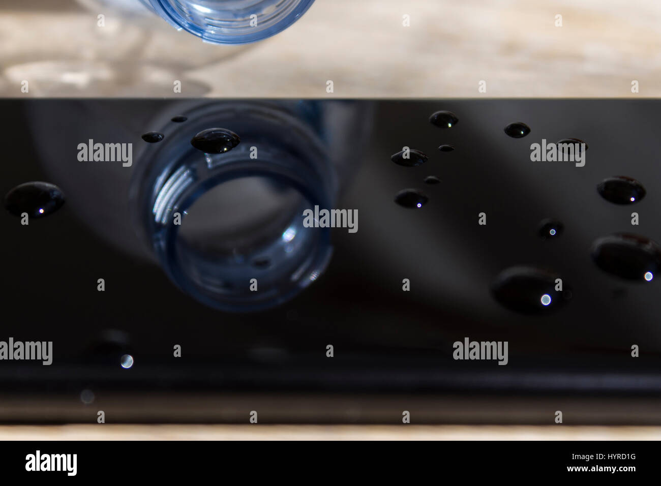 Wasser verschüttet aus einer Flasche auf einem smartphone Stockfoto