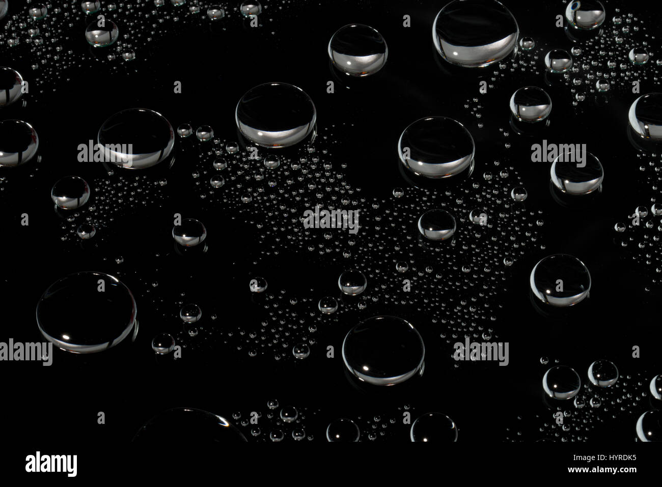 Rund geformte Wassertropfen auf der Glasoberfläche. Dunklen Hintergrund. Stockfoto