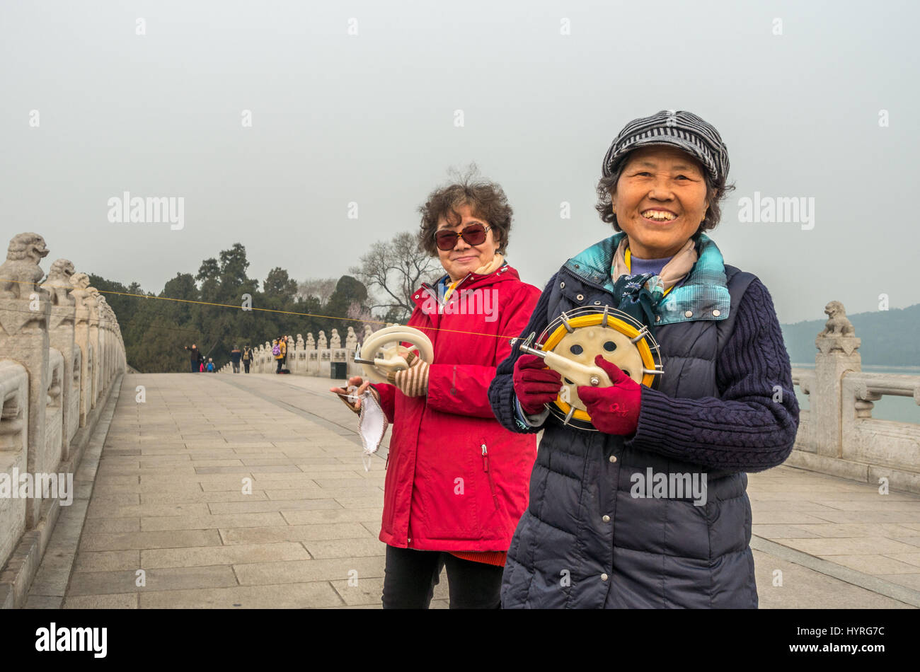 2 Geselligkeit einheimischen lächelnd: Chinesische Frauen flying Kites auf die 17 Bogenbrücke (shiqi Kong Qiao) South Lake Insel, der Sommerpalast, Peking, China Stockfoto