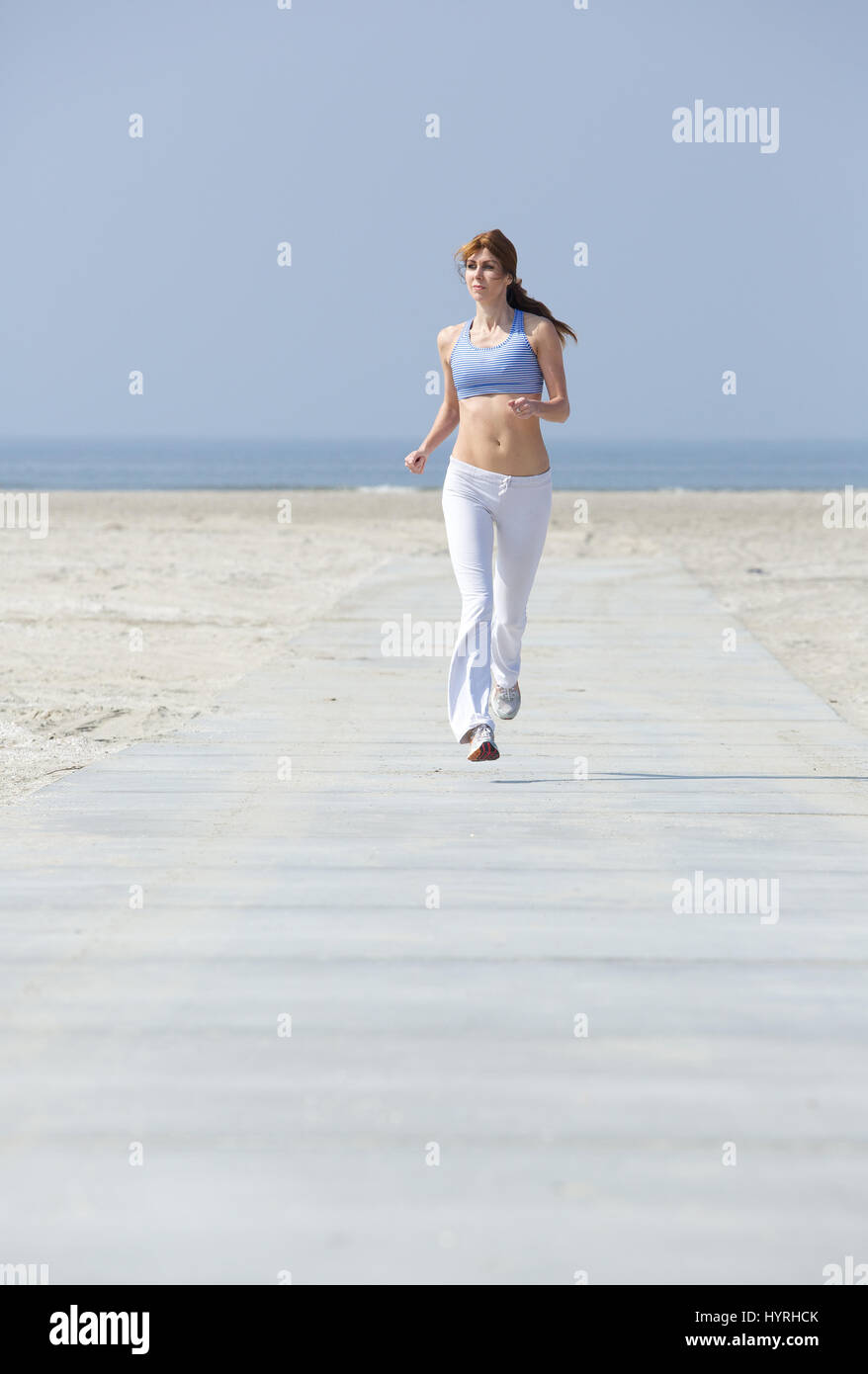 Ganzkörper-Porträt von einem nahen im Alter Frau Übung am Strand joggen Stockfoto
