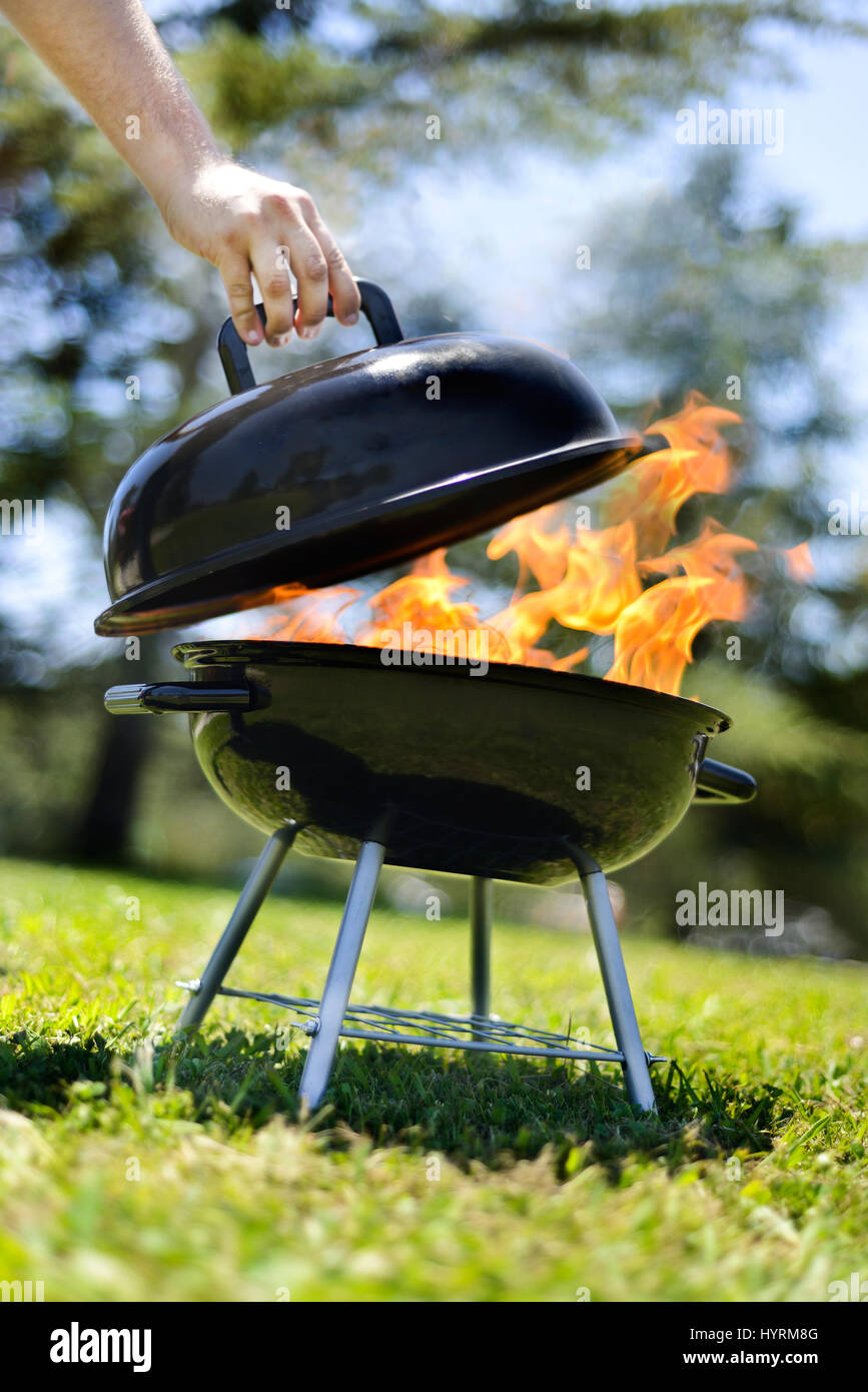 Feuerleitern vom Grill während Deckel angehoben wird. Grillen Burger für ein Picknick in Kalifornien. Stockfoto