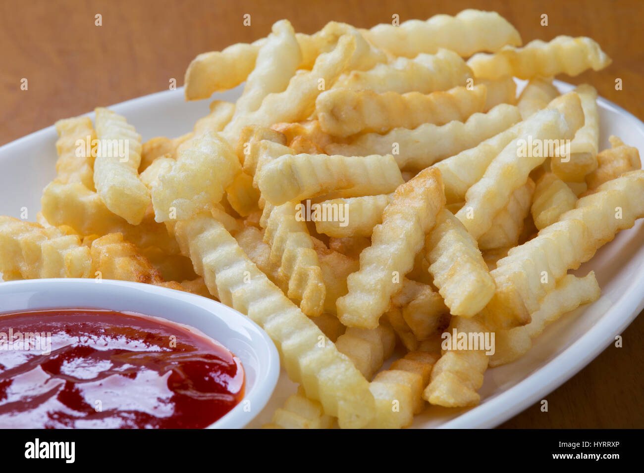 Ein Teller voll mit leckeren Crinkle cut Stil Pommes Frites mit ketchup Stockfoto