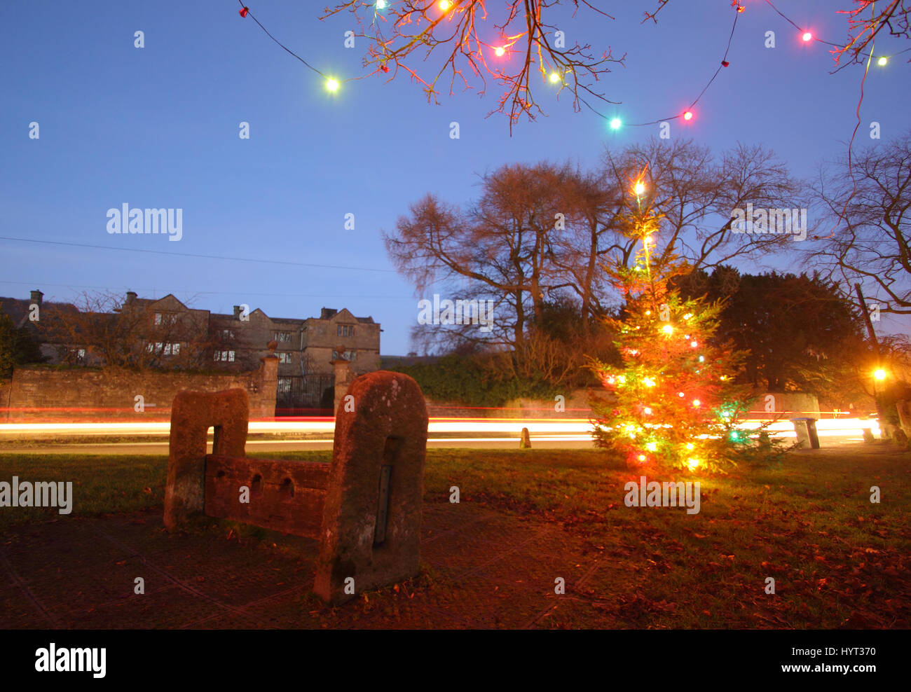 Weihnachtsschmuck durch die Holz- Bestände auf dem Dorfplatz im Eyam, Peak District National Park, England Großbritannien Stockfoto