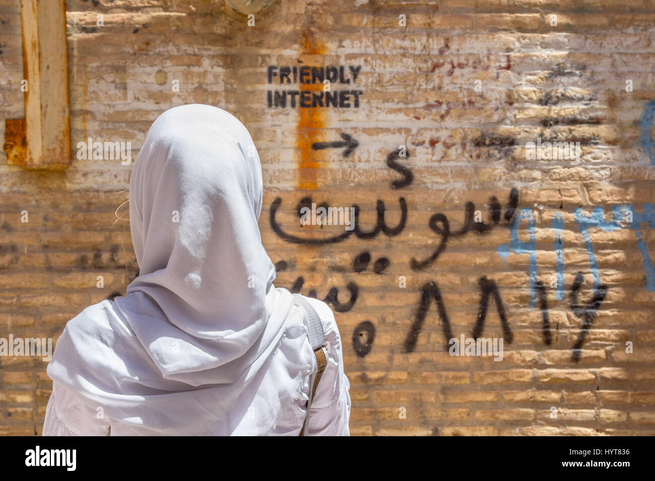 YAZD, IRAN - 18. AUGUST 2016: Verschleierte Frau auf eine Inschrift an der Wand zeigt unzensierte Internet spot Bild einer Frau das Tragen eines sca Stockfoto