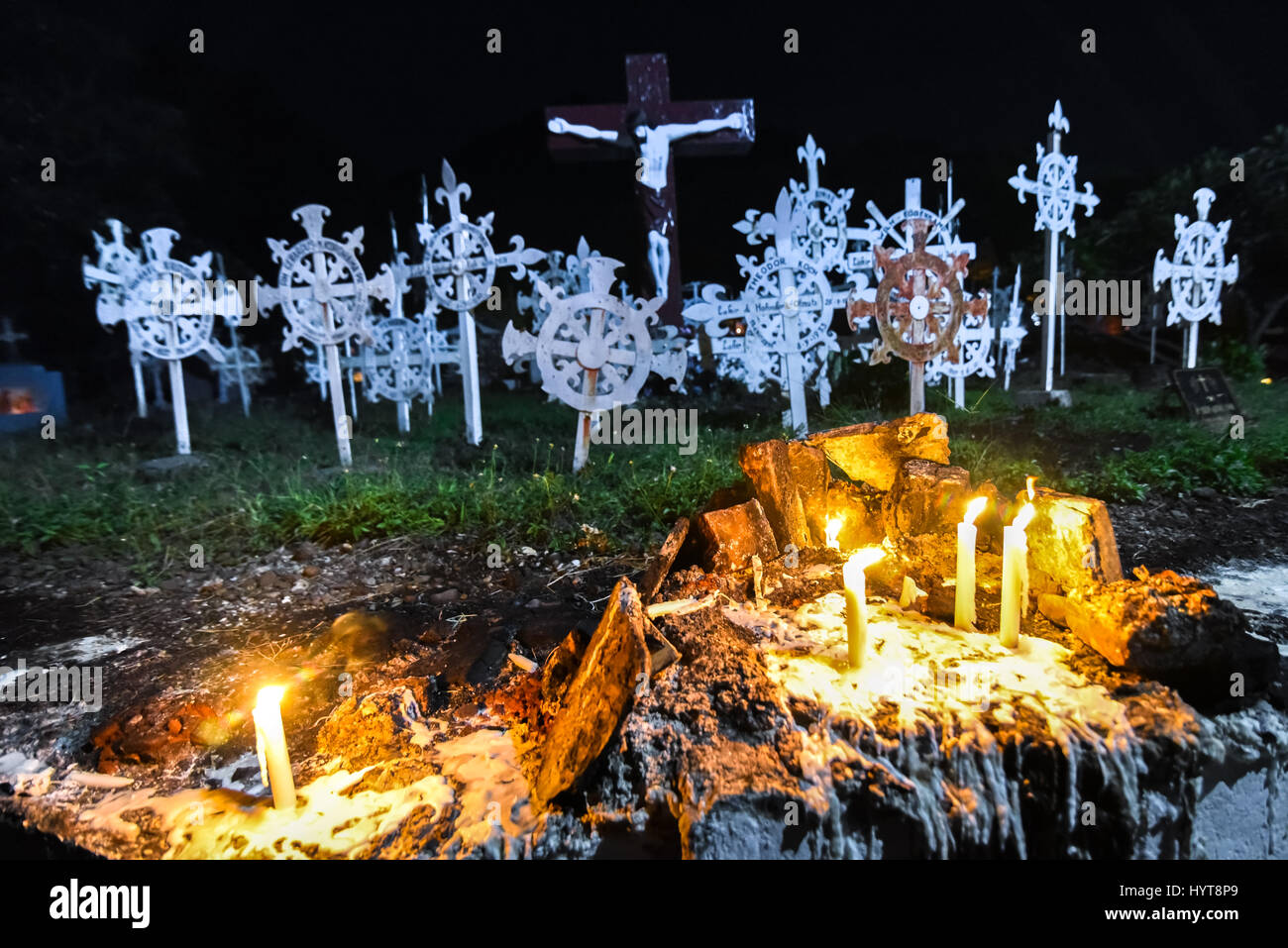 Kerzenlicht in der alten römisch-katholischen Kathedrale Friedhof von Larantuka mit der Statue der Kreuzigung Jesu im Hintergrund. Stockfoto