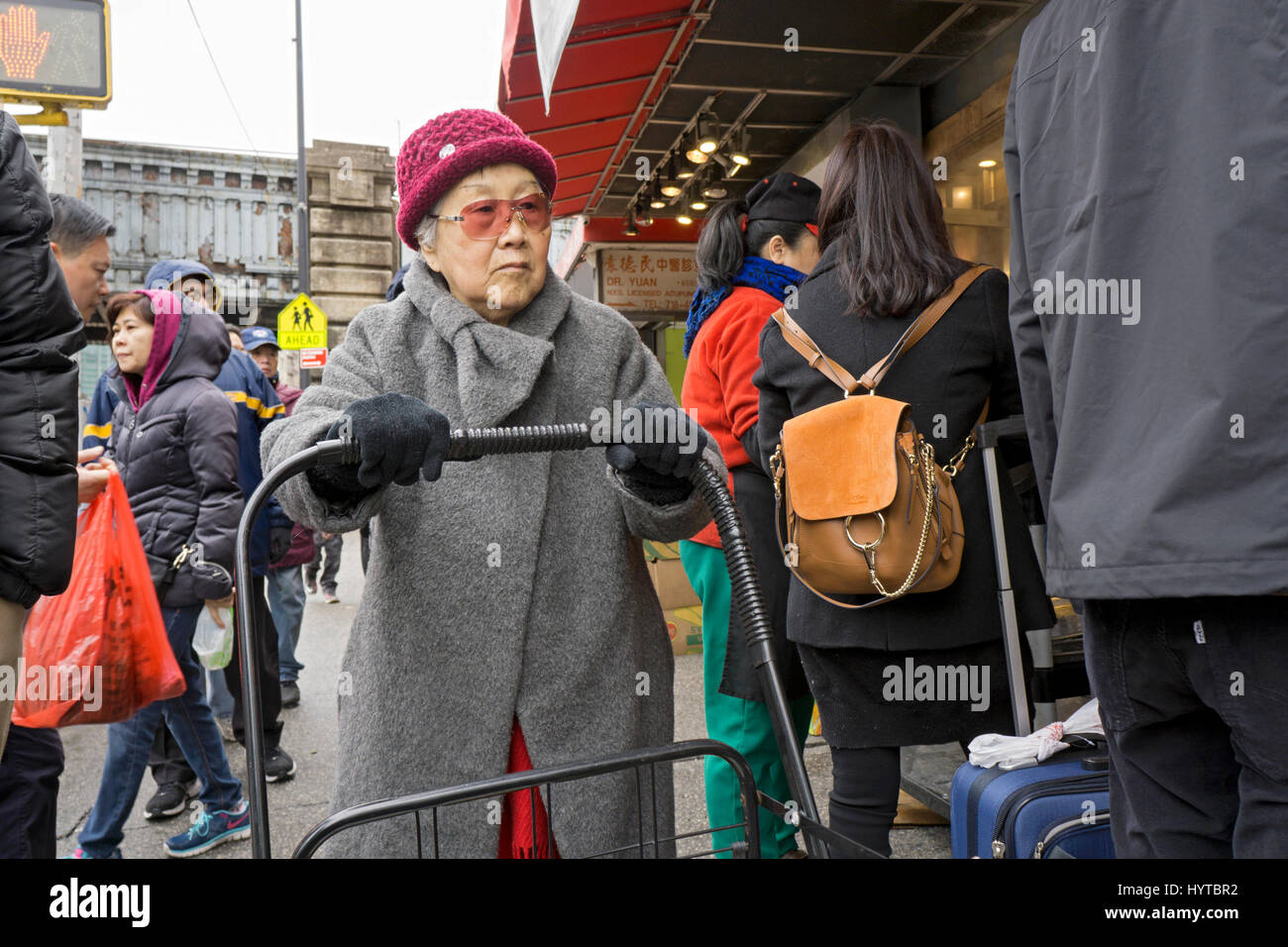 Eine ältere chinesische Amerikanerin außerhalb Einkaufen an einem kalten Tag auf der Main Street in Chinatown, Flushing, Queens, New York City Stockfoto