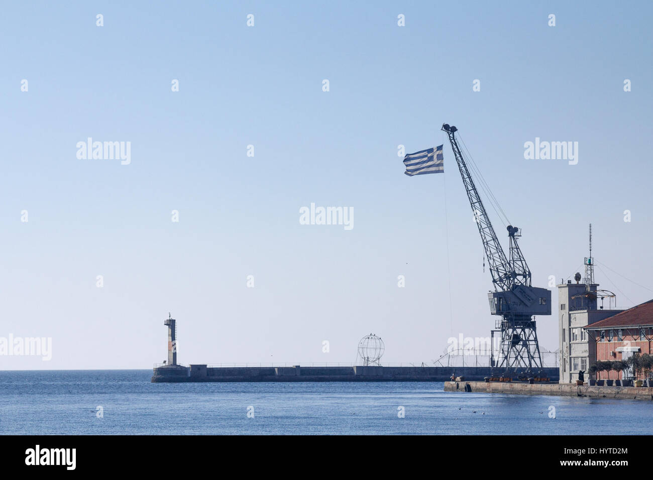 Griechische Flagge auf einem Kran am Pier Thessaloniki, Griechenland-Bild einer griechischen Flagge auf einem Kran gesehen in Thessaloniki, Griechenland, auf dem berühmten Pier von den alten por Stockfoto
