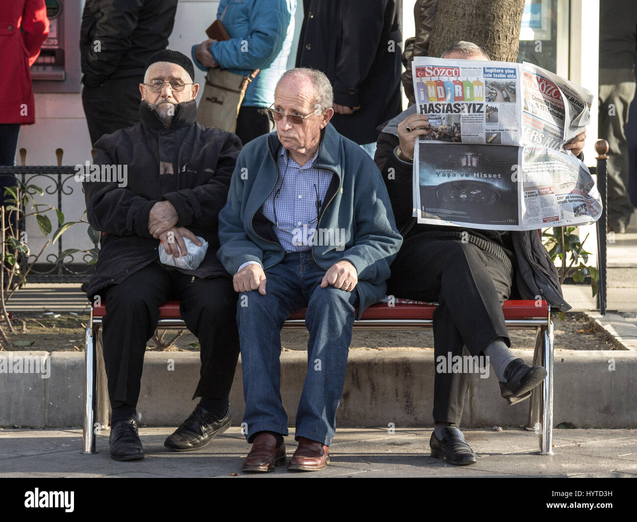 ISTANBUL, Türkei - 28. Dezember 2015: Drei alte türkische Männer sitzen auf einer Bank District Kadiköy auf der asiatischen Seite der Stadt, einer von ihnen Bottled Stockfoto