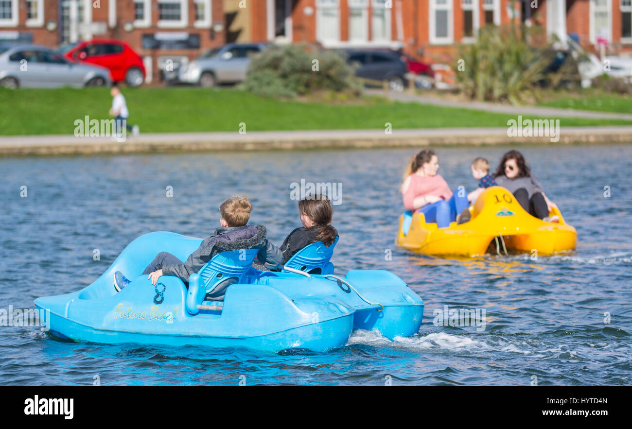 Spaß am Tag heraus. Kinder in Tretboote an einem Frühlingstag auf einen See mit Booten an der Oyster Pond in Littlehampton, West Sussex, England, UK. Stockfoto