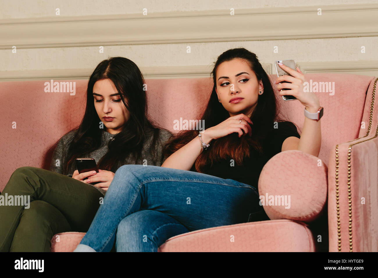 Mädchen auf der Couch mit Smartphones. Horizontale Studioportrait. Stockfoto