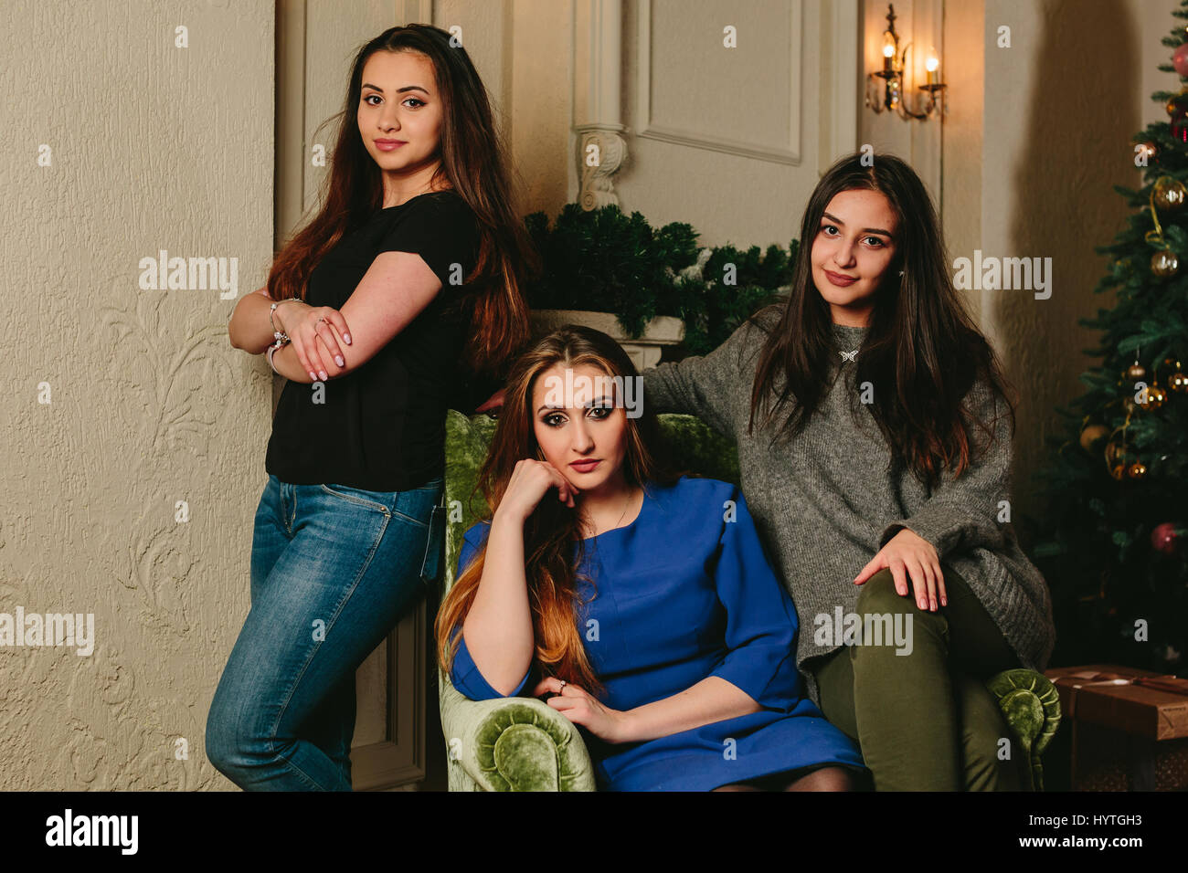 Drei schöne junge Mädchen auf einem Stuhl. Horizontale Studioportrait. Stockfoto