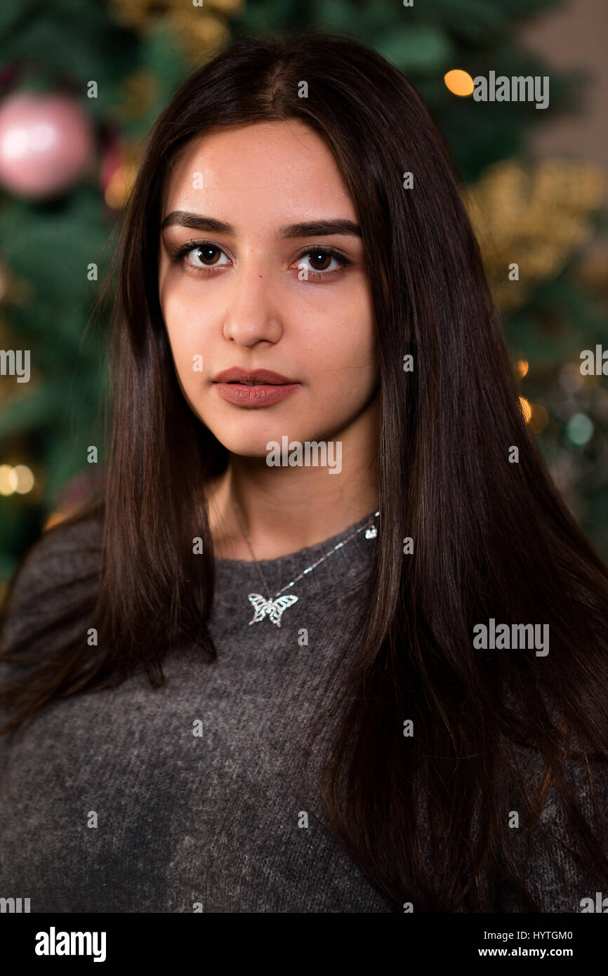 schöne Brünette Mädchen auf dem Hintergrund des Weihnachtsbaumes. Vertikale Nahaufnahme Studioportrait. Stockfoto