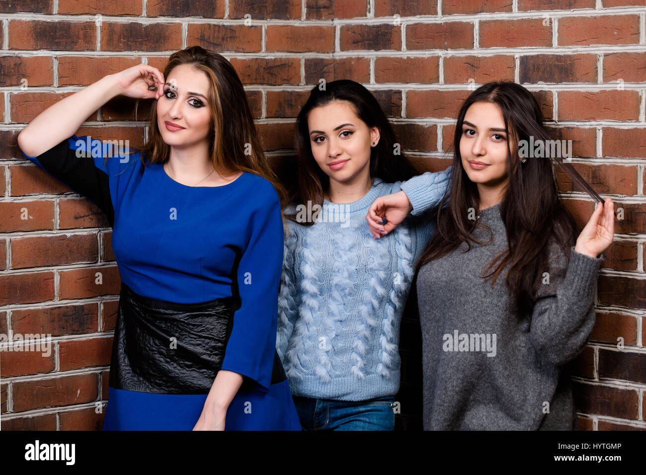 Drei hübsche Freundinnen vor dem Hintergrund der Wand Lächeln. Horizontale Studioportrait. Stockfoto