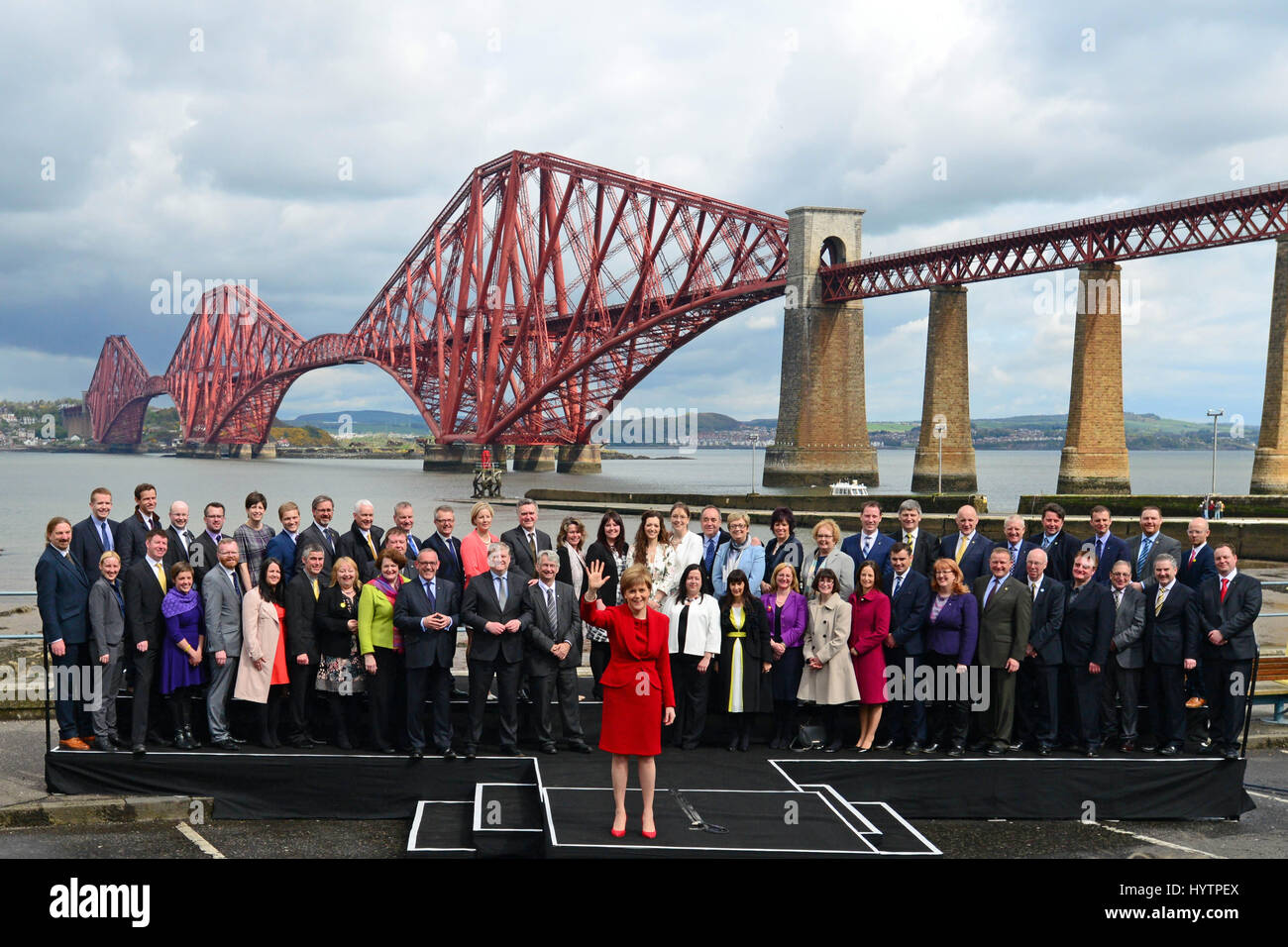 SNP-Führer und schottischen ersten Minister Nicola Sturgeon Wellen zu Medien und Anhänger nach einer Rede von der Gruppe der 56 neu gewählte SNP MPs mit die Forth Bridge im Hintergrund umgeben Stockfoto