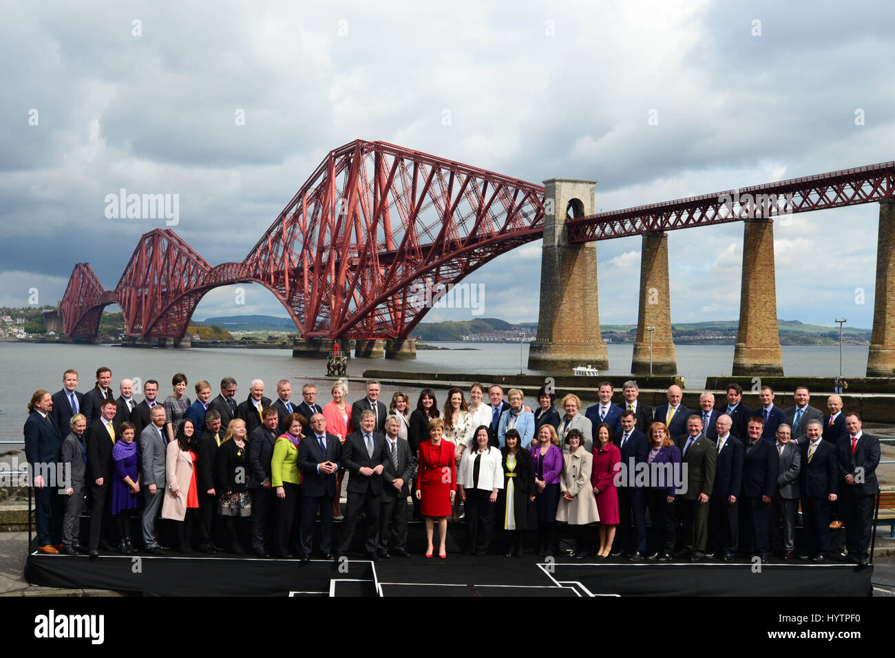 SNP Führer und schottischen ersten Minister Nicola Sturgeon (C, rot) posiert für Fotos mit der Gruppe von 56 neu gewählte SNP MPs mit die Forth Bridge im Hintergrund Stockfoto