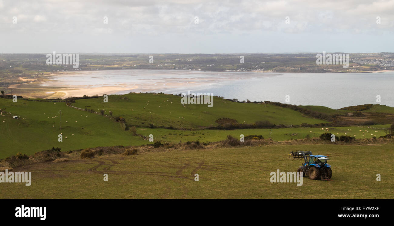 Bauern bei der Feldarbeit über Red Wharf Bay, Anglesey, UK Stockfoto