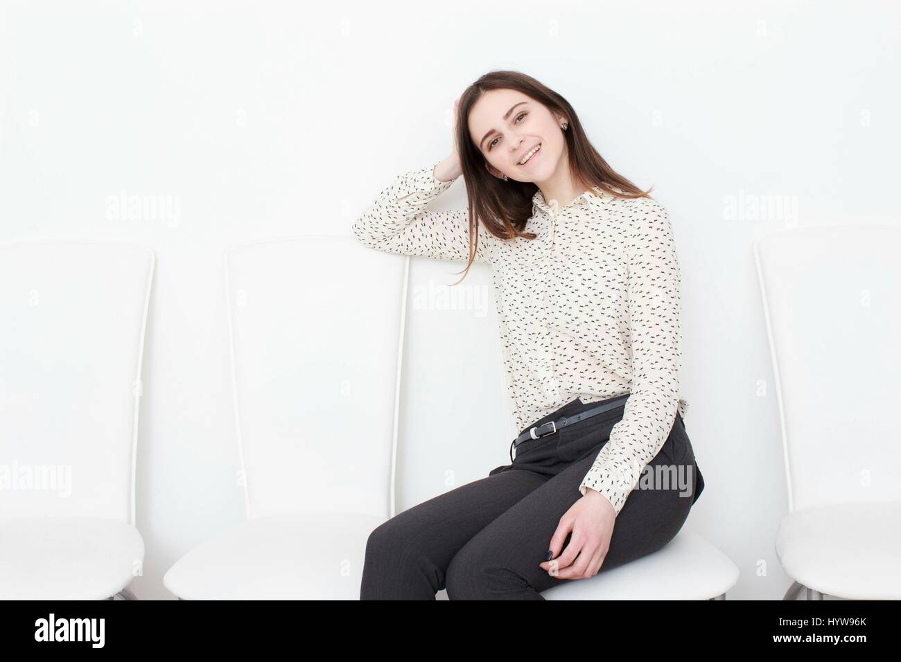 Attraktive Mädchen sitzen auf weiße moderne Stuhl und entspannen Sie sich zu Hause Stockfoto