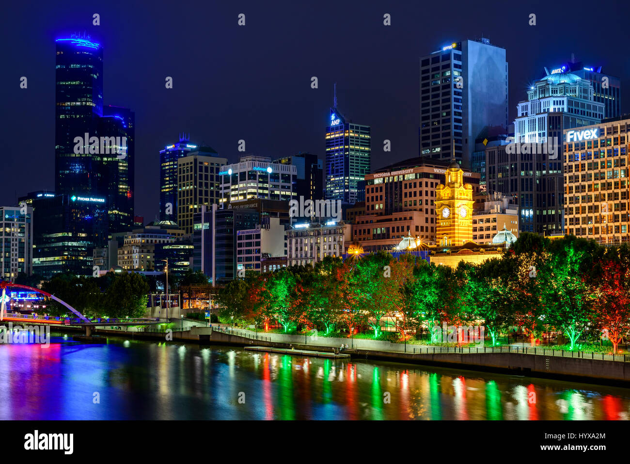 Melbourne, Australien - 27. Dezember 2016: Beleuchtete Gebäude mit Bahnhof im Zentrum in einer Nacht betrachtet über den Yarra River in Melbourne Stockfoto