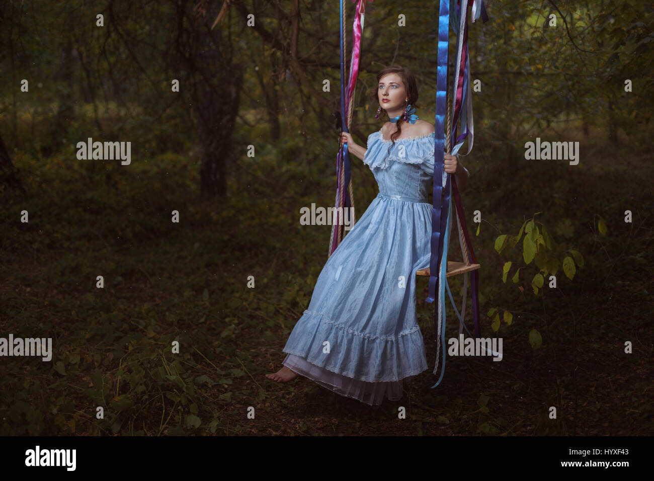 Fabelhafte Retro-Frau in einem smart Kleid im Wald sitzt auf einer Schaukel. Stockfoto