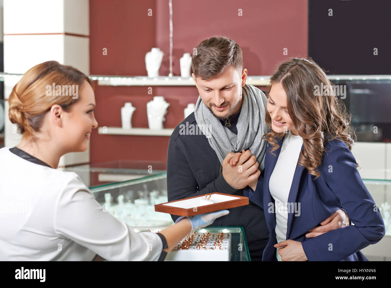 Zeitloses Design. Freundliche weibliche Juwelier helfende junge engagierte Paar Trauringe wählen Stockfoto