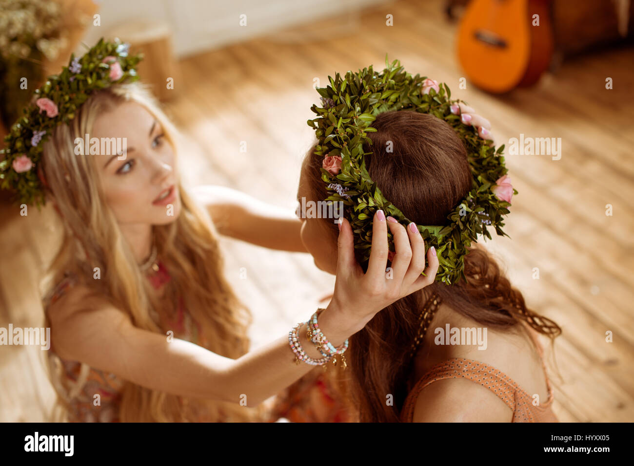 Zwei wunderschöne junge Hippie-Frauen mit langen Haaren tragen Blumenkränzen Stockfoto