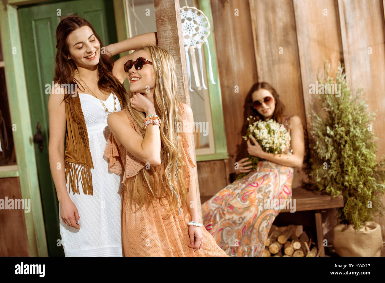Attraktive junge Hippie-Frauen mit langen Haaren tragen Kleider und lächelnd Stockfoto