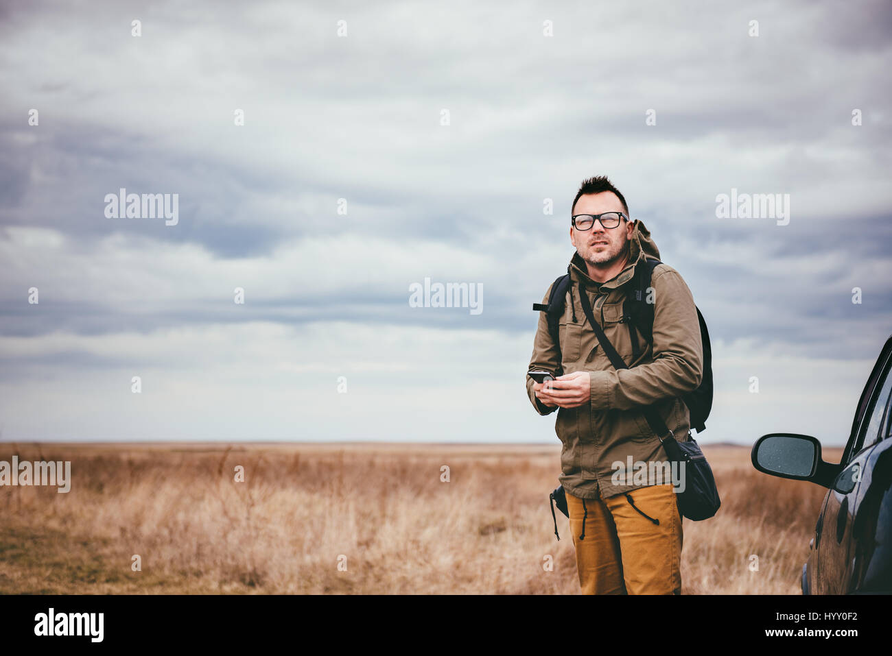 Wanderer im Grünland auf dem Wagen mit Smartphone und man Entfernung stehen Stockfoto