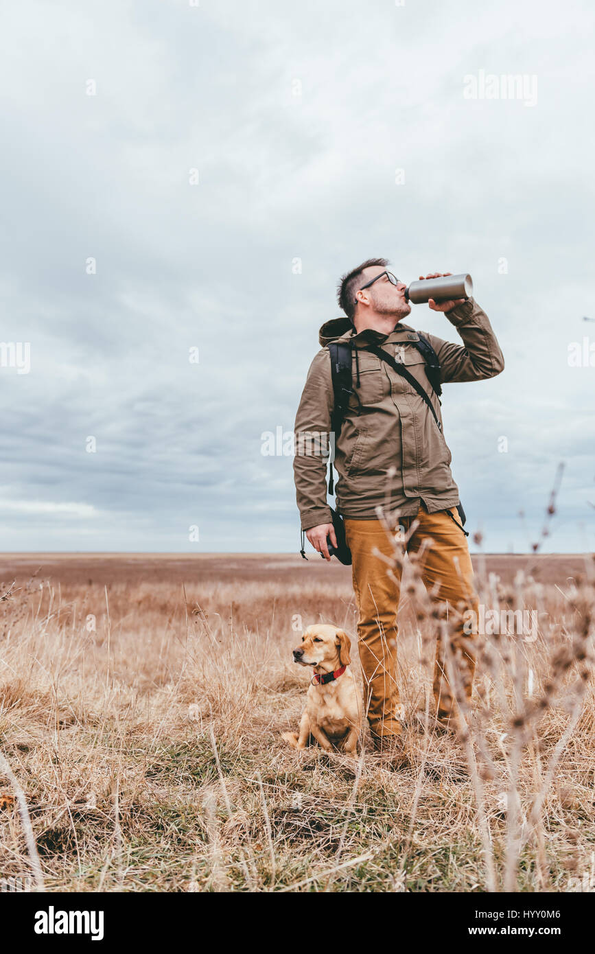 Wanderer im Grünland mit einem Hund und Trinkwasser Stockfoto