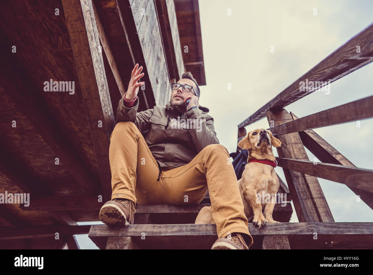 Wanderer auf der Treppe der Rest Blockhütte mit einem Hund sitzen und reden auf Smartphone Stockfoto