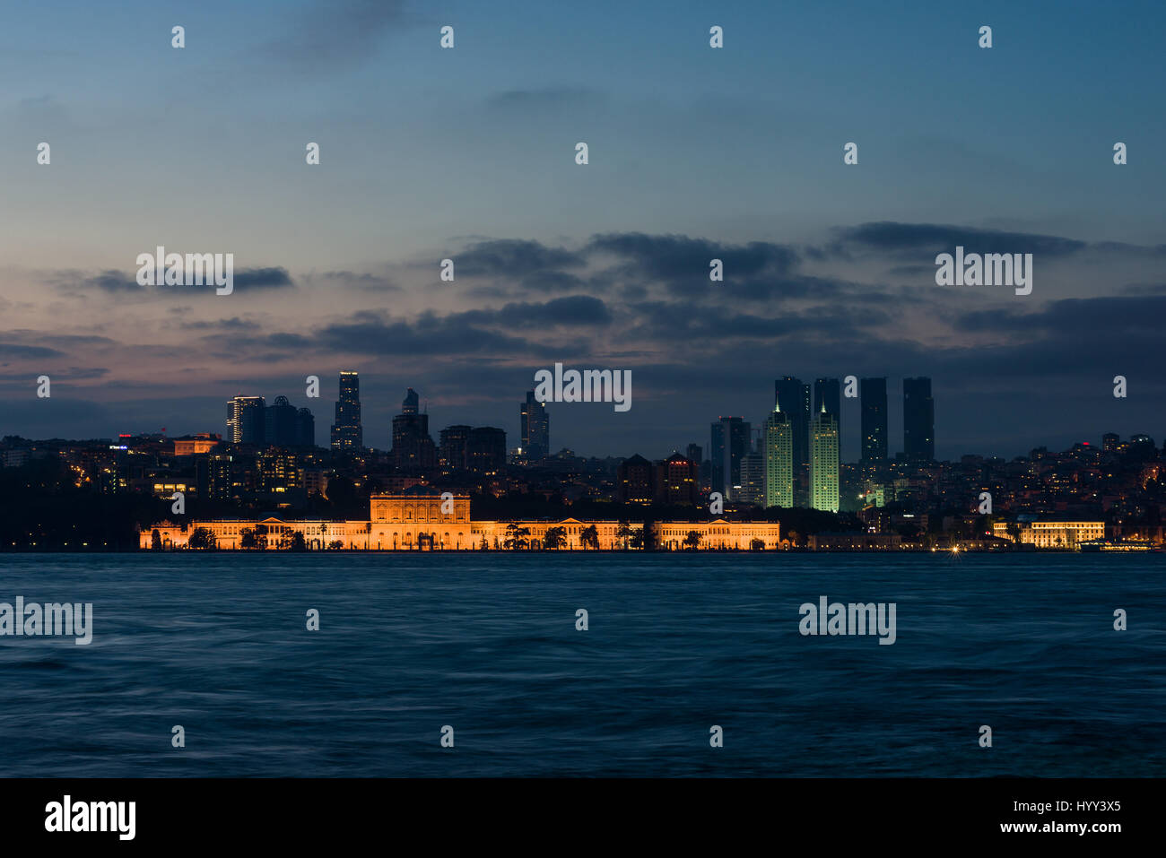 Dolmabahçe-Palast beleuchtet im Abendlicht mit Bosporus im Vordergrund, Istanbul Stockfoto