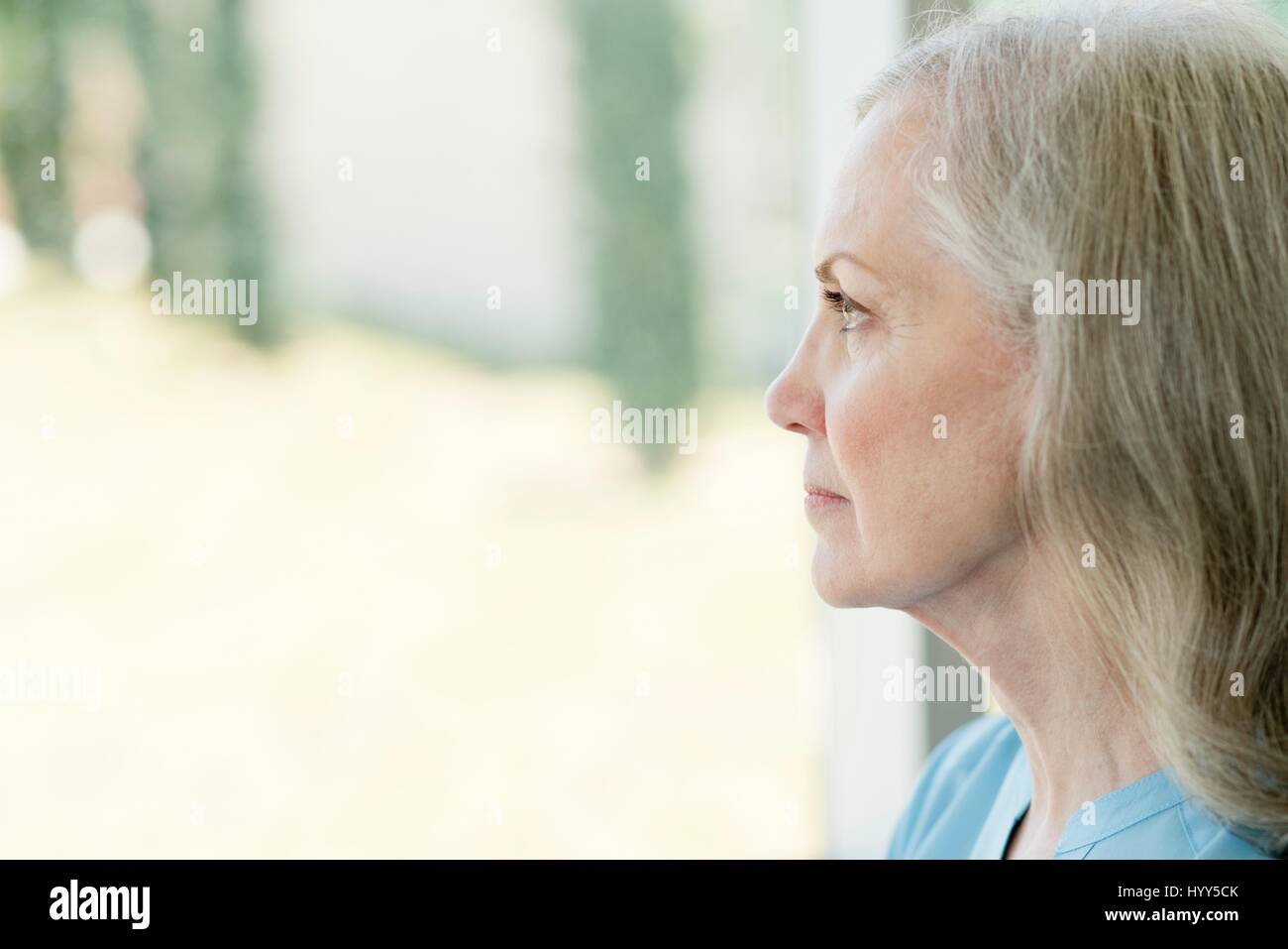 Ältere Frau, die durch Fenster. Stockfoto