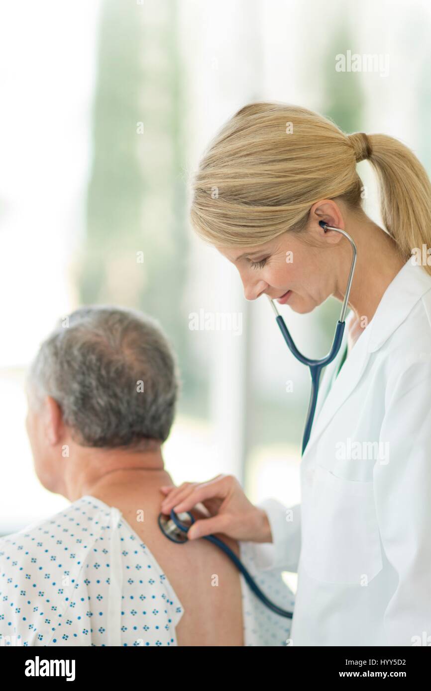 Ärztin mit Stethoskop auf männliche Patienten. Stockfoto